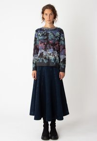 Mitmevärviline kudum-sweerter lillemusterega, ümmargune kaelus. Kombineeritud tumedate denim-seelikutega, millel on voldid. Mustad kuni põlveni sokid.