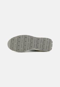 Szürke gumiból készült sneaker talp, tapintott felülettel, amelyen ismétlődő "TOMMY JEANS" márkázás található, ívelt forma és sima élek jellemzik.