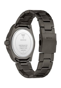Dos d'une montre Guess en acier inoxydable noir, indiquant la résistance à l'eau, le numéro de modèle et les détails du mouvement japonais.