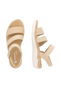 Beige sandalen met drie verstelbare banden, een zachte voetbed en een gestructureerde wigzool met een patroonaccent.