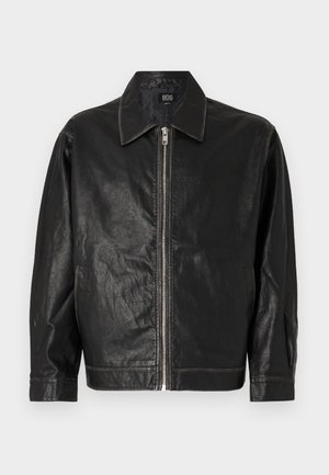 Jachetă din piele neagră cu fermoar frontal, guler ascuțit și buzunare laterale. Prezintă o textură netedă și un design minimal.