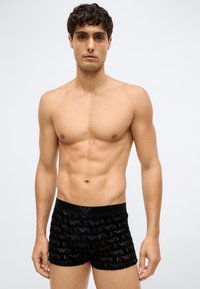 Zwarte boxerbriefs met een transparant meshpatroon en een herhaald logoontwerp. Elastische tailleband. Gladde textuur. Aansluitende pasvorm.