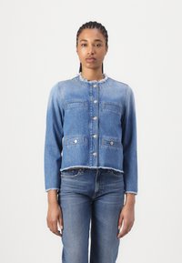 Veste en denim présentant un design court, des bords effilochés, des fermetures à boutons et quatre poches avant, dans une couleur bleu clair.