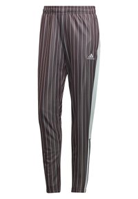 Pantalons de sport marron à fines rayures avec une taille élastique, poches latérales et un panneau bleu clair sur les côtés. Logo Adidas en haut à gauche.