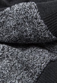 Tela negra con un suave detalle de forro polar gris texturizado. Los materiales en contraste crean una apariencia en capas, resaltando la profundidad y la calidez.