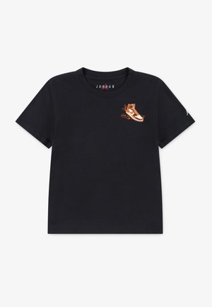 T-shirt en coton noir avec un petit graphique de sneaker orange sur la poitrine et des manches courtes. Encolure ronde simple et coupe décontractée.