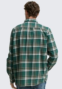 Lange mouw, groen geruit shirt met witte en oranje ruitpatronen, knoopmanchetten en een relaxte pasvorm met een schouderpas ontwerp aan de achterkant.