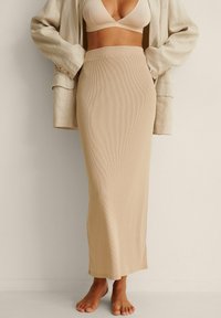 Beige ribbad maxijupe med en åtsittande midja, tillsammans med en ljus oversized blazer, fångad från midjan och ner.