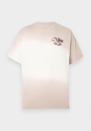 Nike T-shirt in beige tot crèmekleurige ombre, korte mouwen, ronde hals, met een klein bruin logo op de linkerbovenzijde van de borst. Zacht katoenmateriaal.