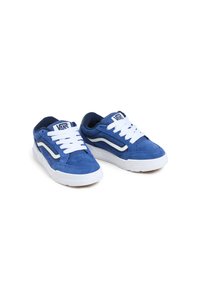 Zapatillas de ante azul con cordones blancos y suelas de goma. Presentan el logo de Vans y una franja blanca en los lados. Material texturizado y forma redondeada.