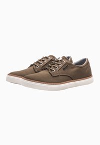 Brown canvas shoes with a rounded shape, white rubber sole, metal eyelets, and lace-up design. Features brown stitching and logo detail.