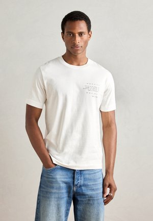 White cotton t-shirt featuring a graphic text design in dark print on the left chest area. Short sleeves and a classic crew neck style.