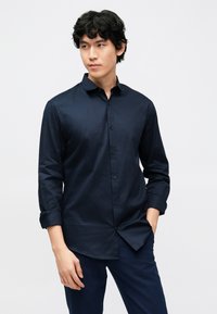 Marineblauw overhemd met knopen, lange mouwen, gladde textuur, slim fit, voorzien van een spreadkraag en netjes uitgelijnde knopen aan de voorkant.