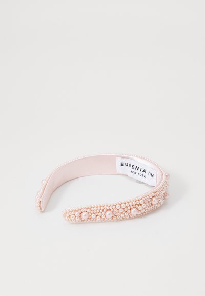 Headband z bisernimi detajli, ki ima mehak roza tekstilni osnovni del okrašen s skupinami biserov in kroglic. Vključuje etiketo znotraj.