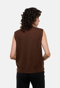 Pull en tricot sans manches marron avec un ourlet côtelé. Texture douce, design ajusté et minimalisme au dos.