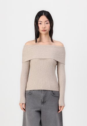 Beige ribbed off-shoulder sweater with long sleeves, fitted design, and a textured surface. Paired with high-waisted gray pants.