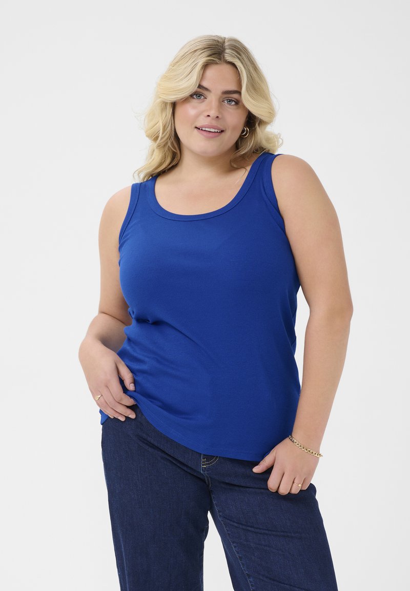 Sininen ilman hihoja tank top, jossa on pyöreä pääntie, valmistettu ribbitetystä puuvillasta, yhdistetty tummansineisiin farkkuihin, joissa on minimaalista tarviketta.