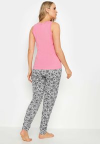 Rosa ärmlös topp som matchas med svarta och vita mönstrade leggings med hjärtmotiv; mjukt tyg och figurnära design.