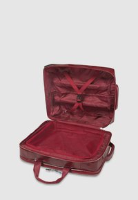 Bolsa de viaje sintética roja con apertura con cremallera, correas interiores y un compartimento de malla para organización. Textura suave y forma rectangular.