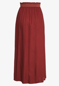 Gonna maxi di un rosso intenso, realizzata in tessuto morbido. Presenta un elastico arruffato in vita e una silhouette fluida con una finitura liscia.