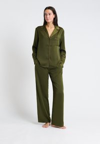 Zielonooliwkowy satynowy zestaw piżamowy składający się z koszuli z guzikami i kieszenią oraz kontrastowym wykończeniem, połączony z luźnymi spodniami straight-leg.