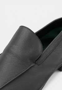 Μαύρο δερμάτινο μοκέτο με υφή, κομψό σχέδιο και χαμηλό προφίλ. Χωρίς ορατά εξαρτήματα ή διακοσμήσεις.