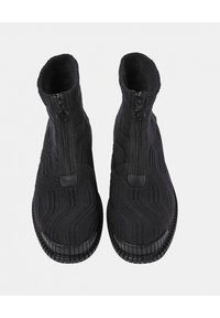 Bottes montantes en tricot noir avec une texture en zigzag, fermeture éclair, semelle en caoutchouc et bout arrondi. Doublure intérieure douce pour le confort.