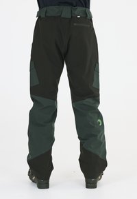 Grüne und schwarze Hose mit tailliertem Design, elastischem Bund, Cargo-Taschen und kleinem Logo an der Unterschenkel. Wasserabweisendes Material.