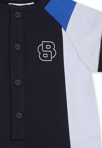 Námořnická, bílá a modrá košile s krátkým rukávem a černými knoflíky označená "BOSS" s bílým obrysem loga "BB" na hrudi.