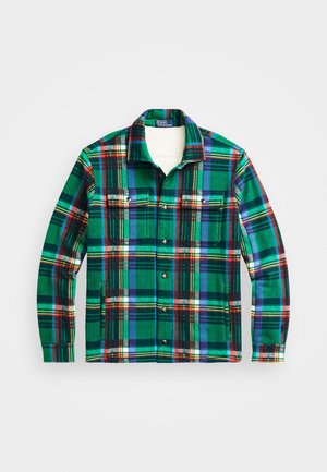 Pitkähihaista vihreää, sinistä ja punaista ruudullista flanellitakkia, jossa on nepparit ja kaksi rintataskua, aseteltuna tasaiseksi valkoiselle taustalle.