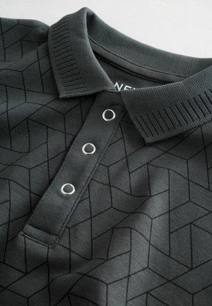 Polo grigio scuro con un motivo geometrico, colletto a costine e tre bottoni metallici decorativi. Tessuto morbido.