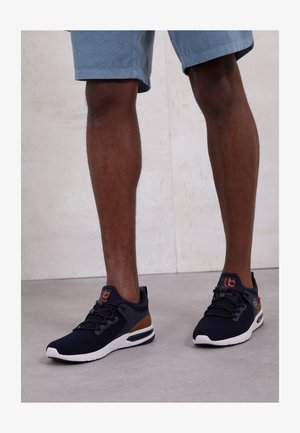 Jūreivių tinkliniai sportbačiai su ruda apdaila, balta padas ir sudėtinga raištelių sistema. Apvalus toe ir paminkštintas apykaklė komfortui.