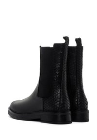 Botas Chelsea negras con un frontal de piel suave y un reverso con un patrón de piel de serpiente texturizado, que cuentan con paneles elásticos en los laterales y una suela resistente.