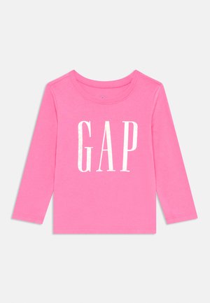 T-shirt à manches longues rose avec un col rond et un logo "GAP" en relief blanc au centre. Matière en coton doux avec une texture lisse.