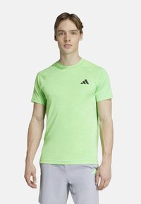 Lichtgroen sport T-shirt gemaakt van ademend materiaal, met een ronde hals, korte mouwen en een zwart Adidas-logo op de borst.