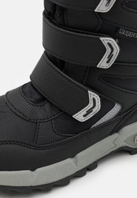 Czarny wodoodporny but z teksturowanego materiału, wyposażony w trzy paski zapinane na rzep, akcenty odblaskowe i trwałą szaro-rubrową podeszwę.