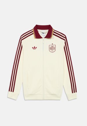 Krema športna jakna z maroon črtami na rokavih, maroon ovratnikom, Adidas logotipom na desnem prsnem delu in grbom španske reprezentance na levem prsnem delu.