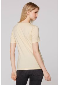 Camiseta de manga corta, de color amarillo claro, hecha de una tela suave, con un corte clásico, cuello redondo y una textura lisa.