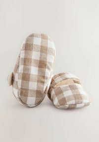 Brune og hvide ternede stofslippers med blødt indre, rund tå og åben bagside. Accentueret med syninger på ydersiden.