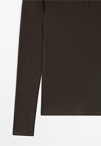 Haut en maille marron foncé à manches longues avec une texture côtelée et un col boutonné sur fond blanc.