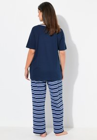 Mörkblå bomullströja med korta ärmar, tillsammans med randiga pyjamasbyxor med växlande blå och vita ränder. Mjuk textur.