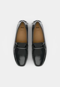 Crne kožne loafers cijenjenog sjaja, s naglaskom u srebrnoj boji i detaljnim šavovima duž rubova. Ime branda: BOSS.