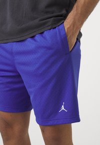 Lilla sportlikke šortid perforatsiooniga tekstuuriga, küljetaskutega ja alumise servaga valge Jordan logo.