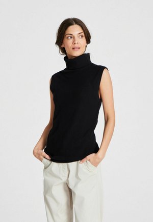Schwarzes ärmelloses Rollkragenoberteil aus weichem Strickstoff, mit hohem Kragen und figurbetontem Design, kombiniert mit hellen, lockeren Hosen.
