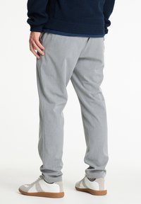 Grijze broeken met een gestructureerde afwerking, voorzien van zijzakken en een relaxte pasvorm, gecombineerd met witte en lichtgrijze sneakers.