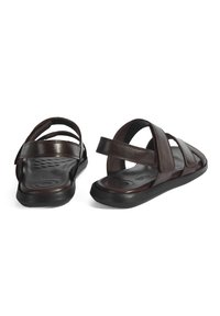 Donkerbruine leren sandalen met meerdere kruisbanden, een gevoerde zool en een zwarte rubberen zool voor grip. Verstelbare achterband voor extra steun.