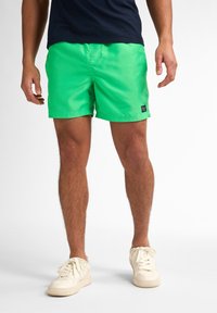 Costume de baie verde realizat din material ușor, având un brâu elastic, buzunare laterale și un mic patch cu logo pe tiv.