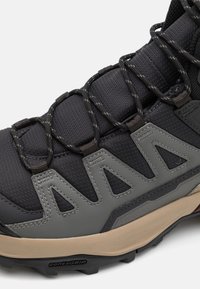 Czarne buty trekkingowe z syntetycznej skóry, szare akcenty, widoczny system sznurowania oraz wytrzymała podeszwa z wyraźnym bieżnikiem.