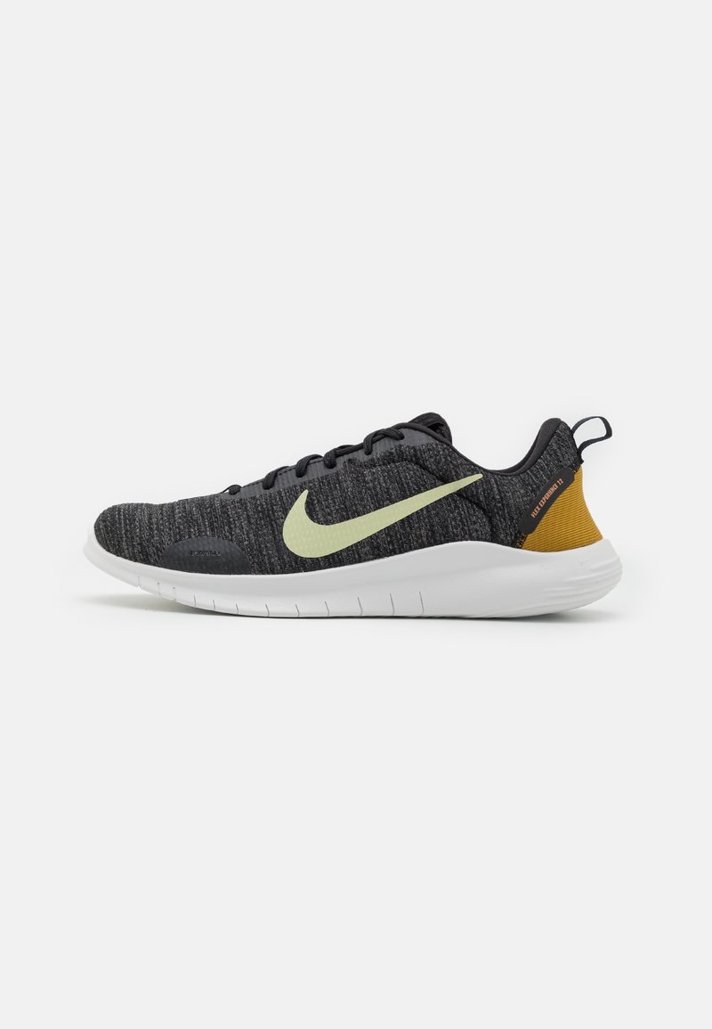 Chaussure de course Nike tricotée noire et grise avec une semelle blanche, un swoosh vert clair, un détail jaune moutarde au talon et des lacets noirs, vue de côté.