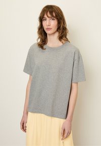 Hallhallane puuvillane t-särk lõdva lõikega, lühikeste varrukatega, ümarate kaelustega ja ilma õmblusteta põhi, millele on lisatud heledalt kollane seelik.